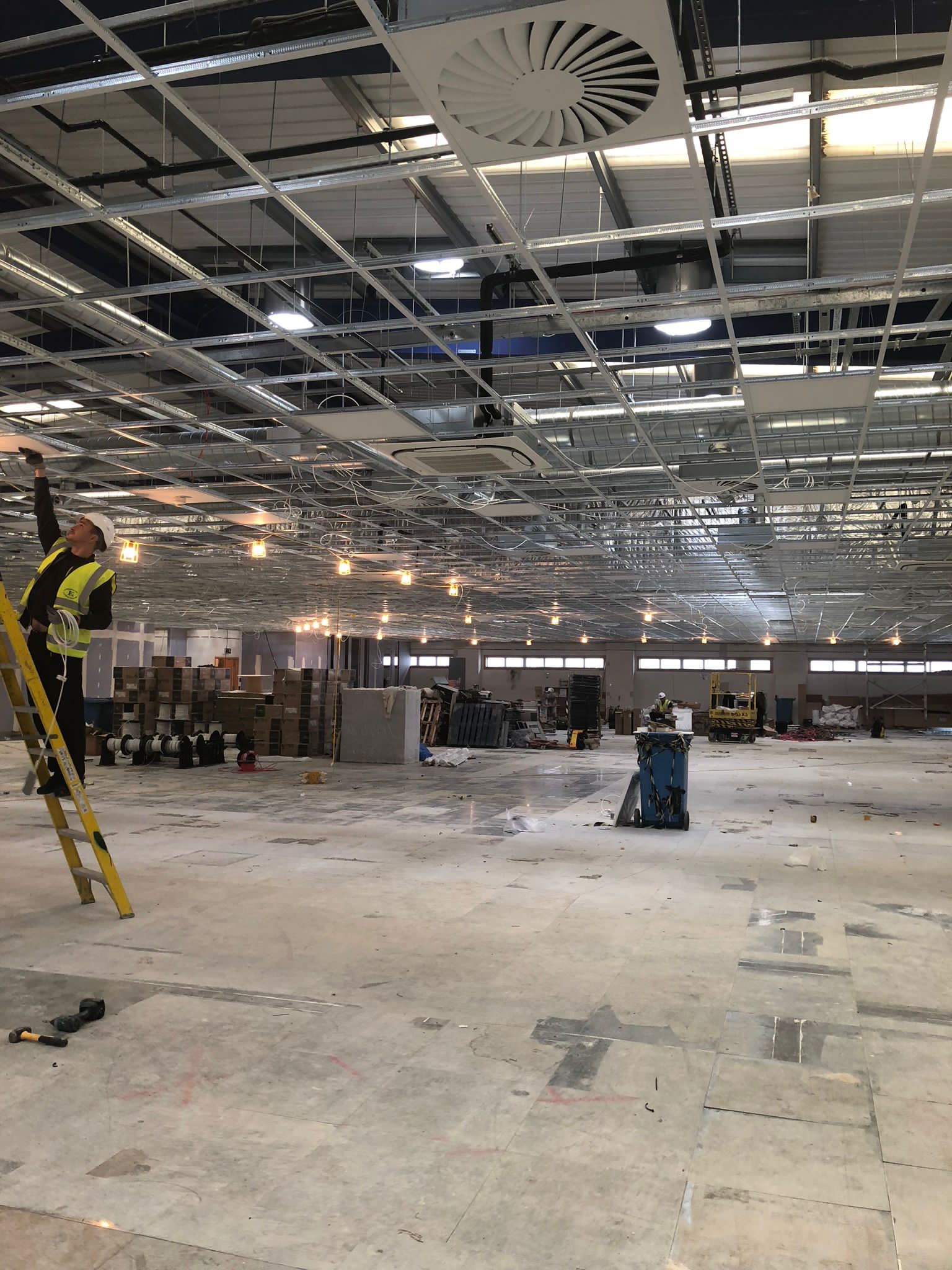 Builder wearing PPE replacing lights on construction site